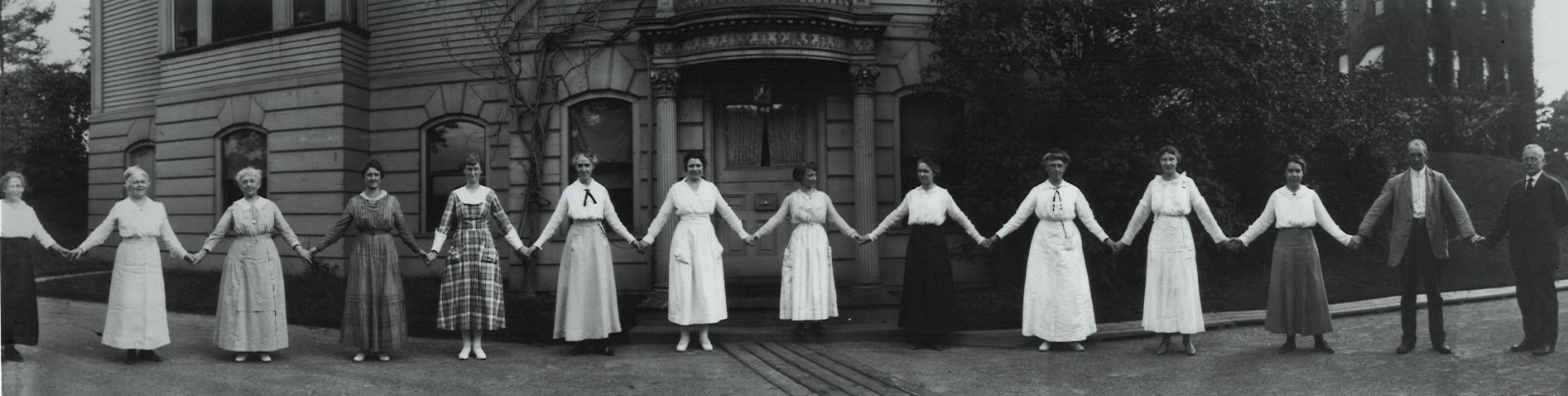 Photo B/W of female computers holding hands in front of the Harvard College Observatory, crica 1900