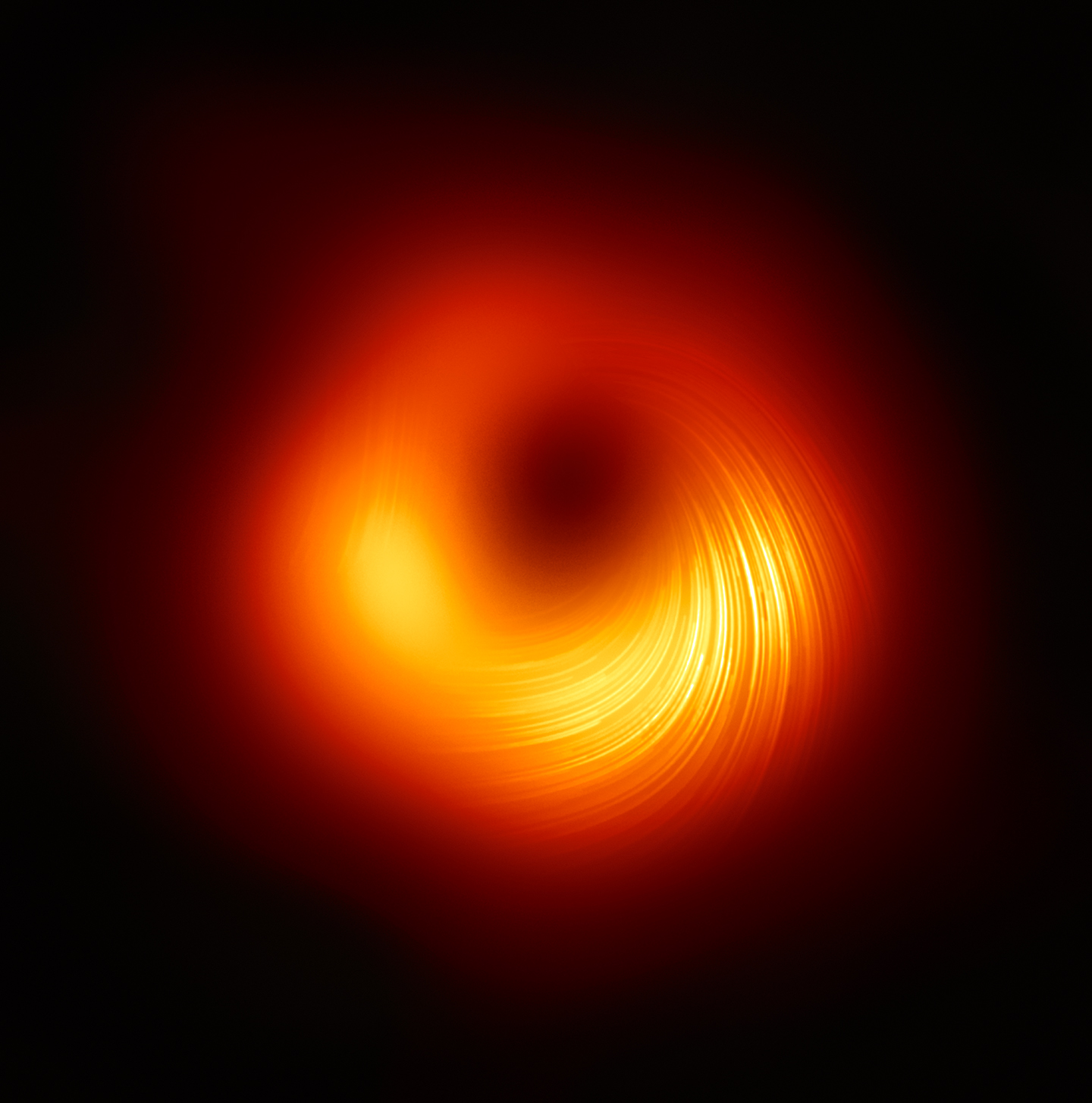 A view of M87's supermassive black hole in polarized light. The lines mark the orientation of polarization, which is related to the magnetic field around the shadow of the black hole.