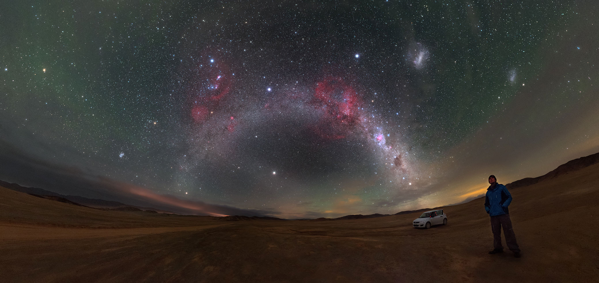 Panorama of the plane of the Milky Way as it arches above the Atacama Desert in northern Chile. The deep exposure brings out an array of sky wonders, including Barnard's Loop — the half pink ring visible above the Milky Way band.