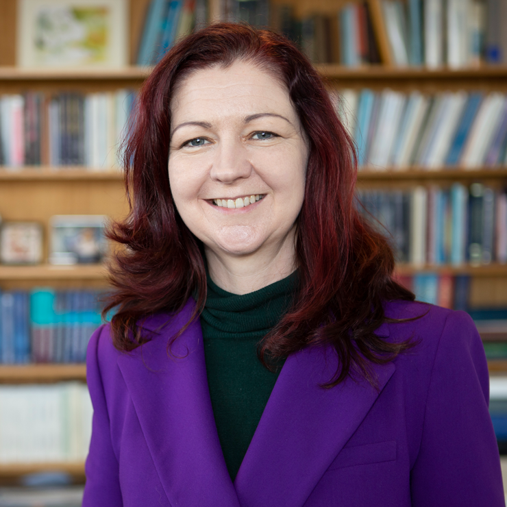 Portrait of Lisa Kewley standing in front of a bookshelf.