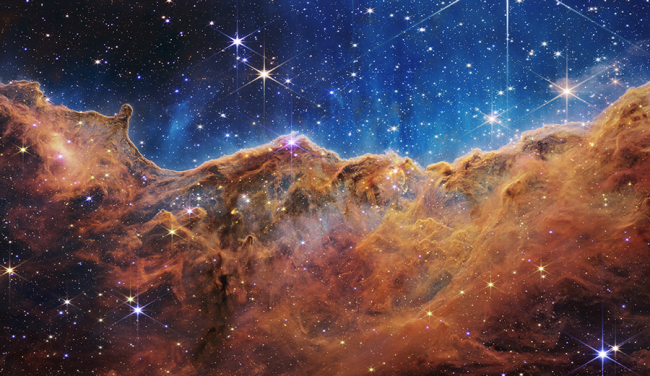 Stars glimmer behind a brown curtain of dust and gas.